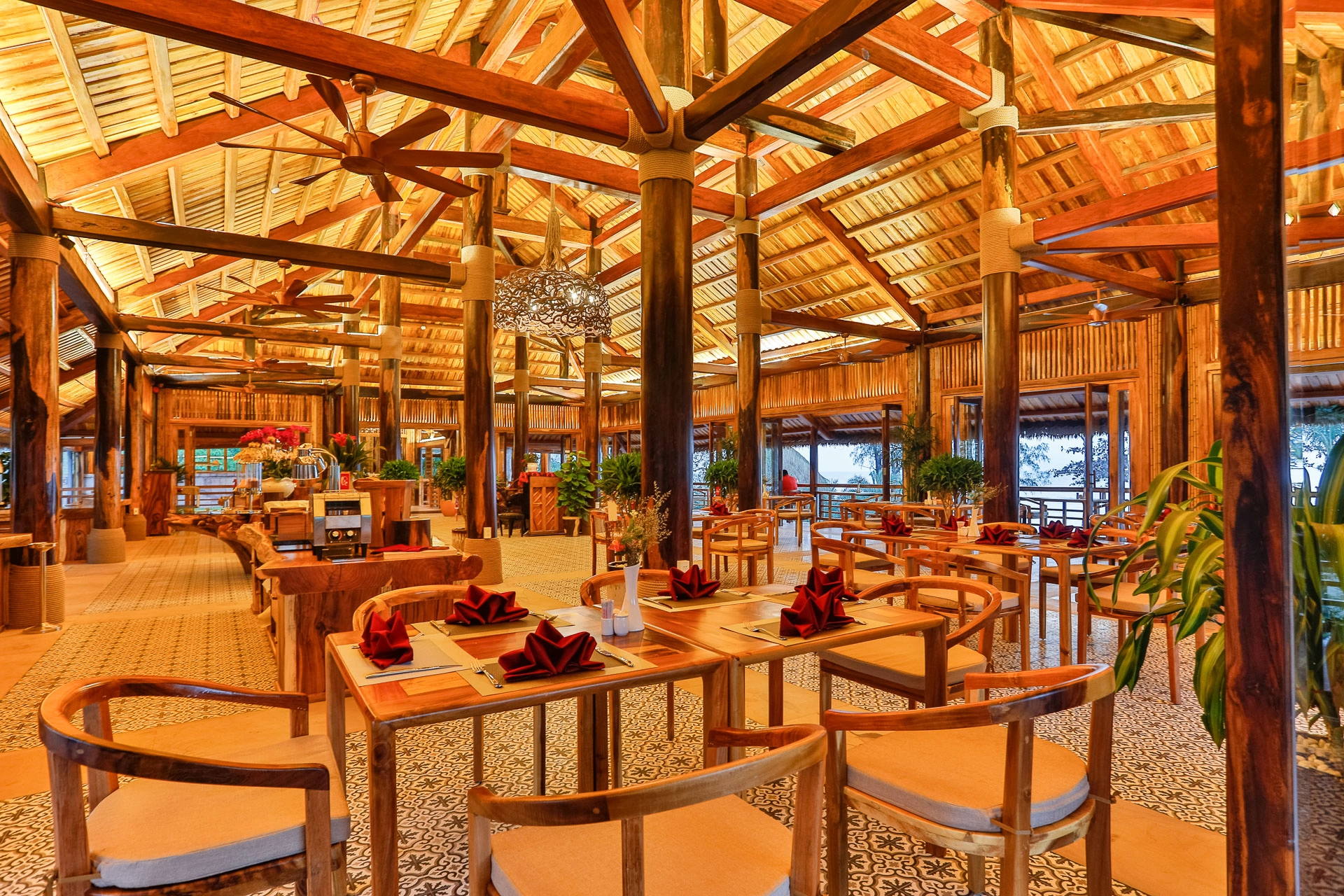 Restaurant interior with exposed timber beams, wooden tables and chairs, ceiling fans and patterned flooring
