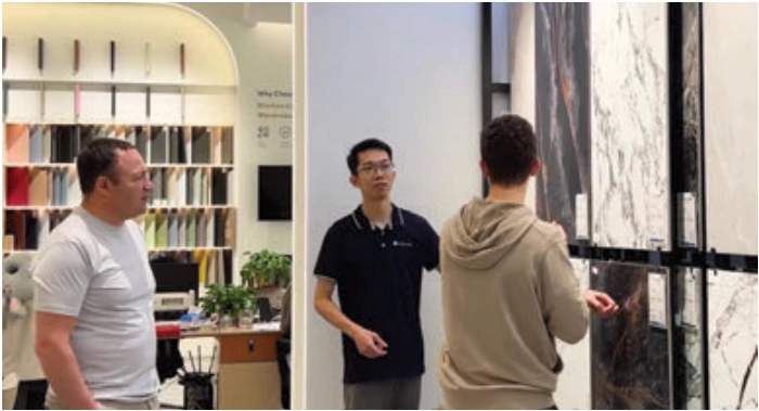 Three people discussing large veined surface samples displayed upright in a showroom
