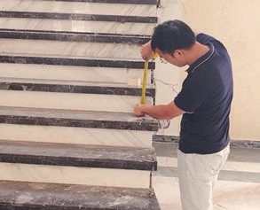 Man measuring a stair riser with a tape measure on a stone staircase