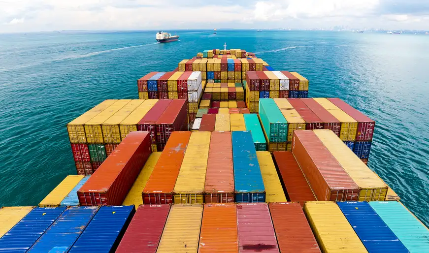 Rows of multicolored containers on a cargo ship deck surrounded by blue sea