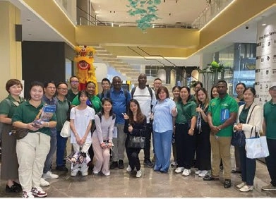 A group posing together in a showroom atrium beneath a decorative lion head
