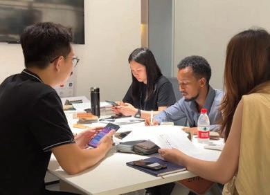 Four people seated around a table reviewing papers and phones during a meeting