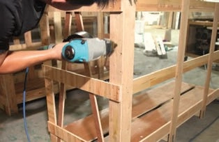 Worker using a pneumatic nail gun to fasten a wooden shipping crate